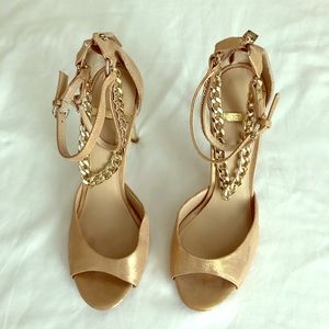 Soft gold heels with connected ankle bracelets.